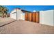 Side view of the home with a wooden gate and gravel driveway at 5312 E Evans Dr, Scottsdale, AZ 85254