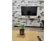 Living room with a brick accent wall, a large TV, and a small workspace at 3119 W Cochise Dr # 225, Phoenix, AZ 85051