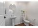 Clean bathroom with pedestal sink, toilet and a metal shelving unit at 23810 W Chipman Rd, Buckeye, AZ 85326