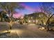Stunning curb appeal with a brick driveway and beautiful landscaping at dusk at 10793 E La Junta Rd, Scottsdale, AZ 85255