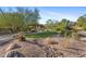 Landscaped backyard with covered patio, putting green, and desert landscaping at 7617 E Presidio St, Mesa, AZ 85207