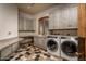 Bright laundry room with modern washer and dryer, ample storage, and hexagon tile floor at 21423 S 147Th St, Gilbert, AZ 85298