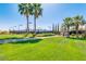 Tennis courts with lush green lawn and palm trees at 22303 N Montecito Ave, Sun City West, AZ 85375