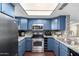 Updated kitchen with blue cabinets, granite counters, and stainless steel appliances at 1601 W Sunnyside Dr # 154, Phoenix, AZ 85029