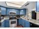 Modern kitchen featuring blue cabinetry, granite countertops, and stainless steel appliances at 1601 W Sunnyside Dr # 154, Phoenix, AZ 85029