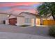 Home exterior view with a wooden garage door at sunset at 16275 W Buchanan St, Goodyear, AZ 85338