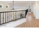 Upstairs hallway with wood-look floors and a metal railing overlooking the main floor at 12641 N 18Th Pl, Phoenix, AZ 85022