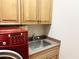 Laundry room with red washer and dryer and wooden cabinets at 42023 N Bridlewood Way, Phoenix, AZ 85086