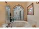 Relaxing bathroom featuring a soaking tub and arched window at 8870 E Greenview Dr, Gold Canyon, AZ 85118
