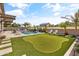 Spacious backyard oasis with a sparkling pool, putting green, and covered patio at 21487 E Arroyo Verde Dr, Queen Creek, AZ 85142