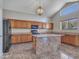 Open kitchen with island, wood cabinets, and black appliances at 8312 W Pioneer St, Tolleson, AZ 85353