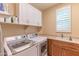 Bright laundry room with washer, dryer, cabinets and a utility sink at 16917 W Sheridan St, Goodyear, AZ 85395