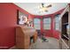 Home office with built-in desk, exercise bike, and red walls at 18516 W Sweet Acacia Dr, Goodyear, AZ 85338