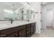 Bathroom with dark vanity, double sinks, and a frameless shower at 16173 S 181St Ave, Goodyear, AZ 85338