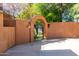 Elegant archway with an ornate iron gate opens to a serene backyard at 15972 N 115Th Way, Scottsdale, AZ 85255