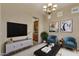 Living room with a modern TV stand and two teal armchairs at 42929 W Castle Cove Cir, Maricopa, AZ 85138