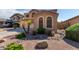 Two-story house with tan exterior, arched windows, landscaping, and a rock pathway at 16079 W Williams St, Goodyear, AZ 85338