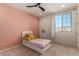 Bright bedroom with a twin bed, large window, and soft pink wall at 23095 E Mewes Rd, Queen Creek, AZ 85142