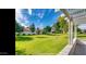 Spacious backyard with grassy lawn, mature trees, and a pergola-covered patio at 13035 W Ballad W Dr, Sun City West, AZ 85375