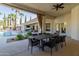 Covered patio boasts a dining area and views of the pool and lush landscaping at 8575 E Sharon Dr, Scottsdale, AZ 85260