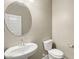 Small bathroom with a pedestal sink, toilet and round mirror at 1471 S 239Th Dr, Buckeye, AZ 85326