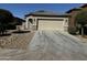 Tan one-story house with a two-car garage and gravel driveway at 20216 W Desert Bloom St, Buckeye, AZ 85326