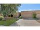 Tan stucco home with a two-car garage and a mature olive tree in the front yard at 7955 E Solano Dr, Scottsdale, AZ 85250