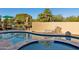 Curved pool and spa with patio furniture and desert landscape at 3044 Ironwood Rd, Carefree, AZ 85377