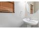 Small bathroom with a pedestal sink and round mirror at 40375 W Helen Ct, Maricopa, AZ 85138