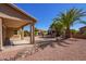 Backyard with covered patio, desert landscaping, and palm trees at 42915 W Kingfisher Dr, Maricopa, AZ 85138