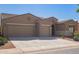 Tan two-story house with a three-car garage and desert landscaping at 42915 W Kingfisher Dr, Maricopa, AZ 85138