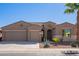 Tan two-story house with a three-car garage and desert landscaping at 42915 W Kingfisher Dr, Maricopa, AZ 85138