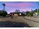 Backyard with a mix of desert landscaping and green plants with a beautiful sunset sky at 12903 W Skyview Dr, Sun City West, AZ 85375