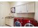 Bright laundry room, featuring granite countertops, white cabinets, and red LG washer and dryer at 16349 E Links Dr, Fountain Hills, AZ 85268