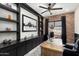 Home office with built-in shelving, large desk, and exposed brick wall at 20428 W Elm Dr, Buckeye, AZ 85396