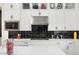 Modern kitchen with white cabinets, black tile backsplash and stainless steel appliances at 20428 W Elm Dr, Buckeye, AZ 85396