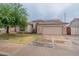 Tan one-story house with a tile roof, two-car garage, and a tree in front at 7951 E Posada Ave, Mesa, AZ 85212