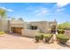 Front view of a tan stucco home with a wooden door and desert landscaping at 10044 E Graythorn Dr, Scottsdale, AZ 85262