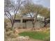 Desert landscape surrounds this modern stucco home with a landscaped lawn and mature trees at 10044 E Graythorn Dr, Scottsdale, AZ 85262