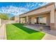 Spacious backyard with a covered patio, artificial turf, and a stone retaining wall at 15528 E Chicory Dr, Fountain Hills, AZ 85268