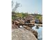 Serene backyard with a stone fireplace, pond, and comfortable seating at 9808 E Honey Mesquite Dr, Scottsdale, AZ 85262