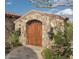 Stone entry gate with wooden doors and landscaping at 9808 E Honey Mesquite Dr, Scottsdale, AZ 85262