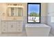 Elegant bathroom with a freestanding tub, white cabinetry, and a large window at 2041 N Orchard --, Mesa, AZ 85213