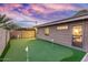 Putting green in backyard at dusk with detached garage in background at 8325 E Crestwood Way, Scottsdale, AZ 85250