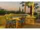 Covered outdoor kitchen with stone bar and seating at 13232 W Los Bancos Dr, Sun City West, AZ 85375