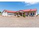 Single story home with red metal roof, covered porch, and gravel driveway at 5604 S 225Th Ave, Buckeye, AZ 85326