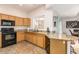 Kitchen boasts wood cabinets, granite counters, and black appliances at 7959 W Waltann Ln, Peoria, AZ 85382