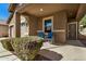 Covered porch with two blue striped chairs and flowering bushes at 22608 W Gardenia Dr, Buckeye, AZ 85326