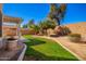 Landscaped backyard with covered patio, grassy area, and mature trees at 980 S 220Th Ln, Buckeye, AZ 85326