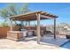 Outdoor kitchen with pergola and stainless steel appliances at 16918 S 180Th Dr, Goodyear, AZ 85338